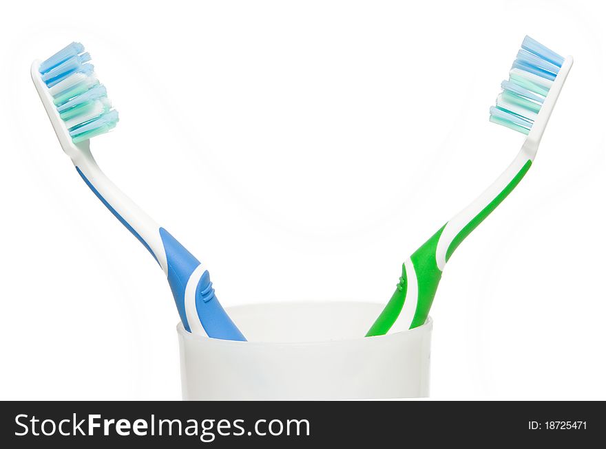 Two toothbrushes in glass. Focus is pointed at the bristle brushes