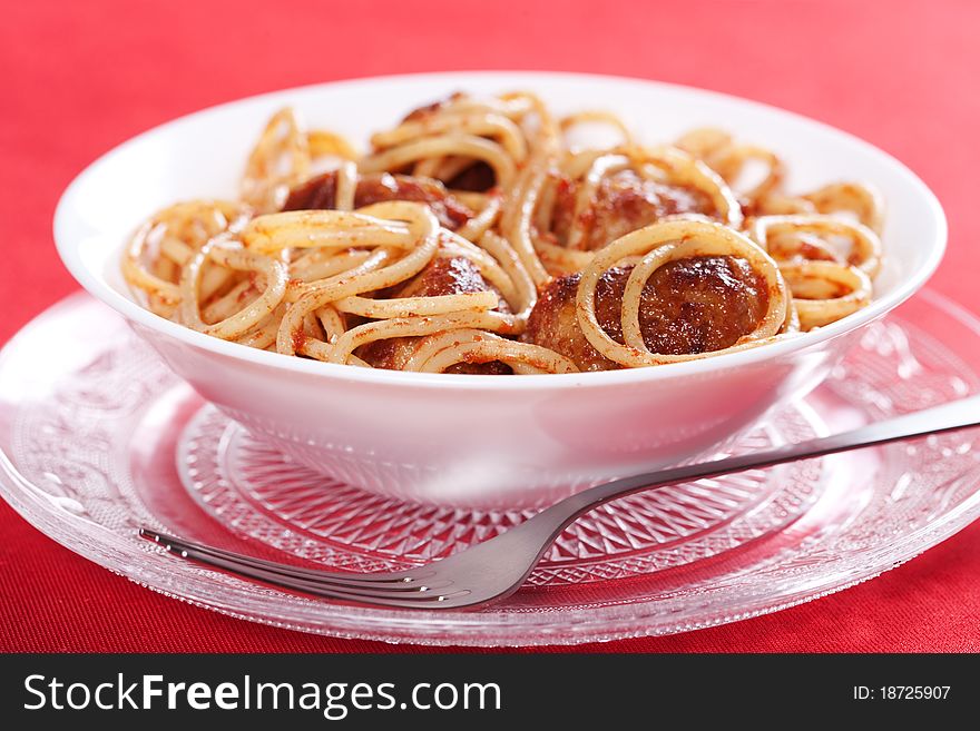 Pasta with meatballs and tomato sauce on red background