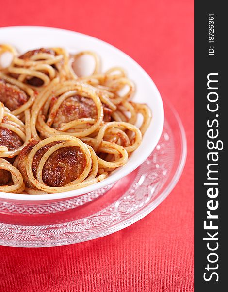 Pasta with meatballs and tomato sauce on red background