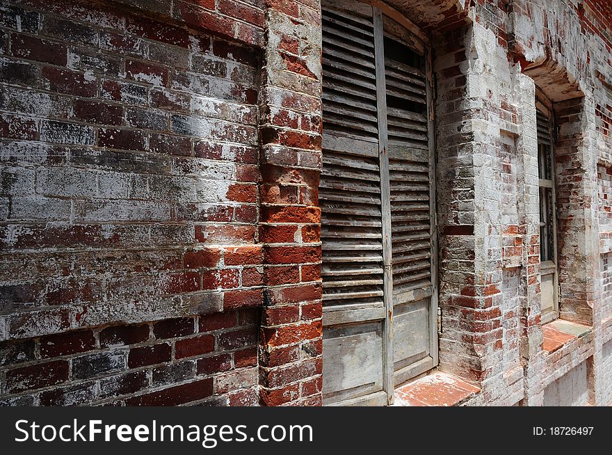 Old brick wall with red bricks and broken wooden windows.