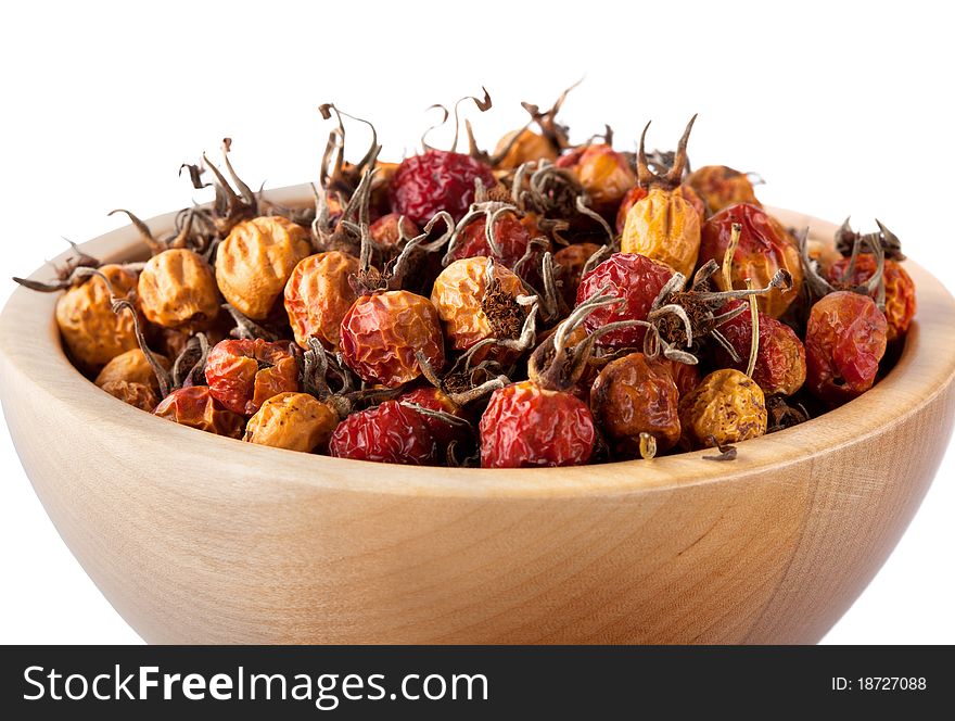 Dried rosehips in wooden bowl isolated on white