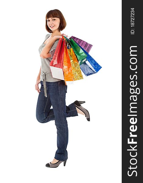 Smiling young woman with rainbow colored shopping bags isolated on white