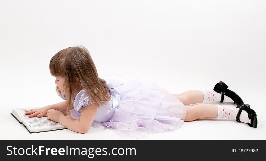 Young girl in pink dress lying and reading a book. Young girl in pink dress lying and reading a book