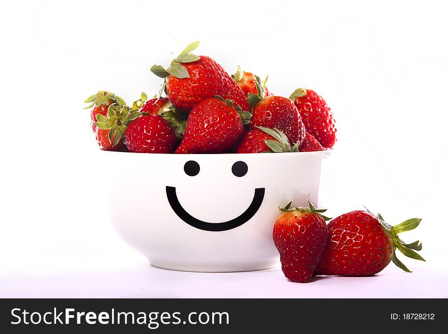 View of a smiley bowl filled with strawberries isolated on a white background. View of a smiley bowl filled with strawberries isolated on a white background.