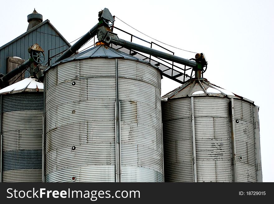 Grain storage bins in winter with an overcast sky. The overcast sky serves as a white background, helping with copy space. Grain storage bins in winter with an overcast sky. The overcast sky serves as a white background, helping with copy space.