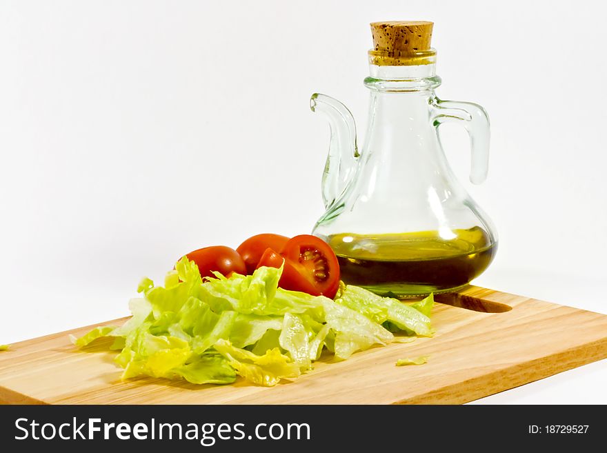 Tomatoes lettuce and olive oil on a wooden chopping board. Tomatoes lettuce and olive oil on a wooden chopping board