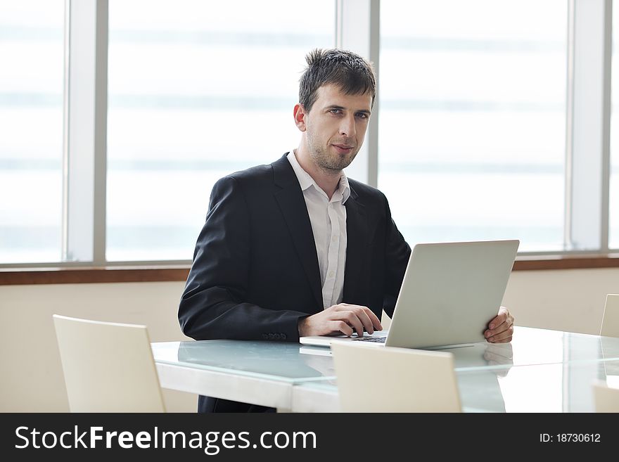 Young business man lawyer with laptop alone in big bright   conference room. Young business man lawyer with laptop alone in big bright   conference room