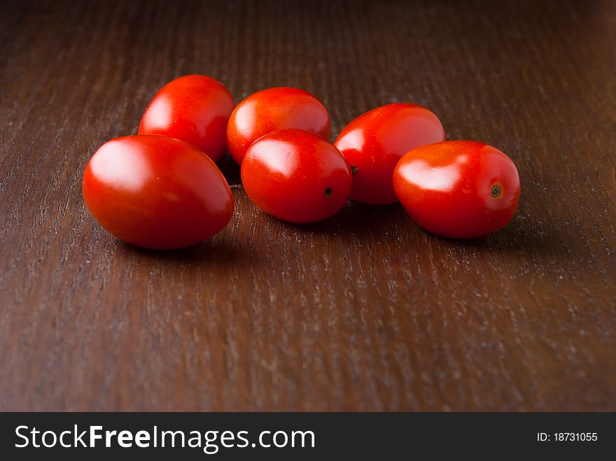 Six red fresh Cherry tomatoes on a wood table. Six red fresh Cherry tomatoes on a wood table