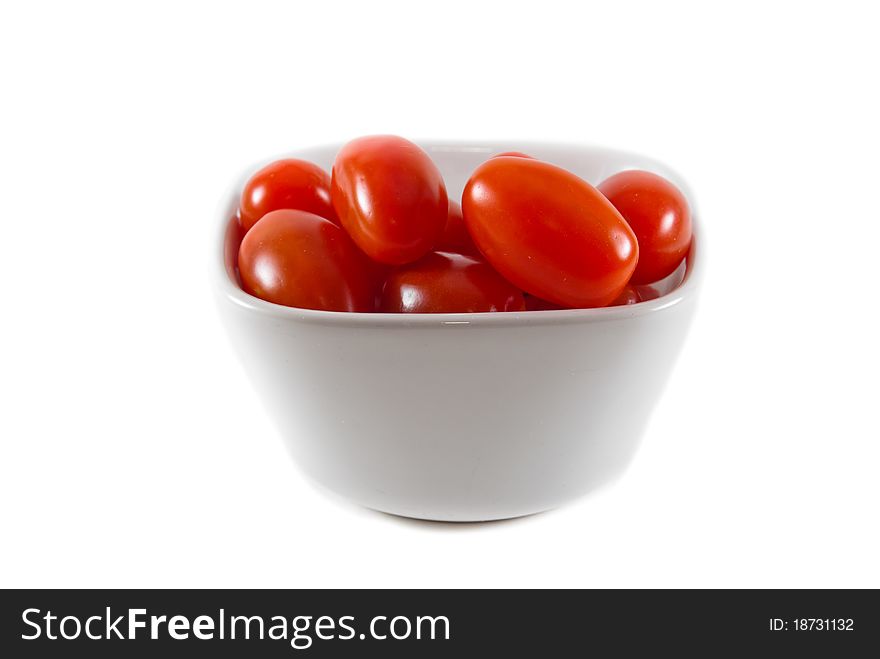 A white ceramic bowl of fresh red cherry tomatoes on a white isolated background. A white ceramic bowl of fresh red cherry tomatoes on a white isolated background.