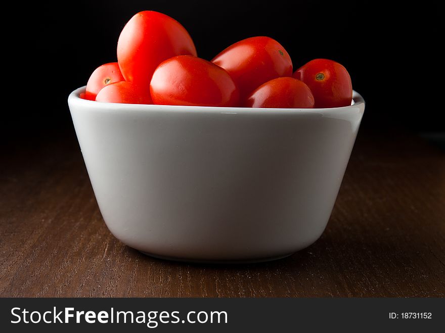 A Bowl Of Cherry Tomatoes On A Wood Table