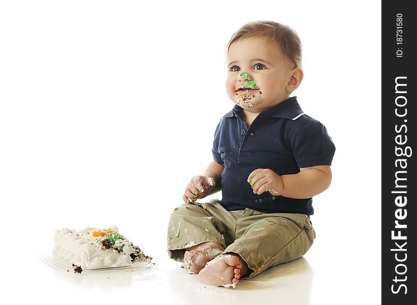 An adorable baby boy happyily digging into a small cake. Isolated on wite. An adorable baby boy happyily digging into a small cake. Isolated on wite.