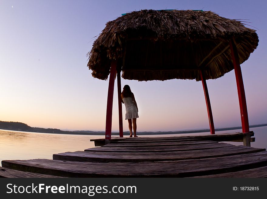 A beautiful girl enjoys Guatemalan sunrise on a wharf at lake Peten. A beautiful girl enjoys Guatemalan sunrise on a wharf at lake Peten.