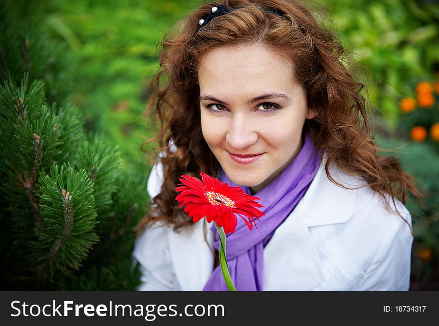 Young woman with red flower gerbera on plant background