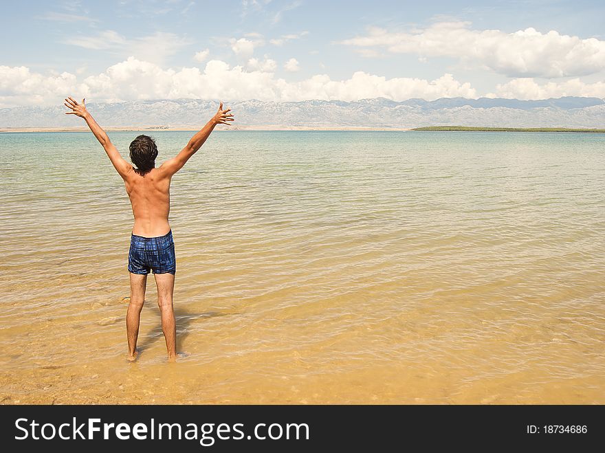 A young happy man raising hands on a beach. A young happy man raising hands on a beach