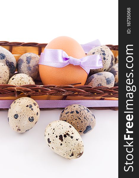 Quail and chicken eggs in basket over white