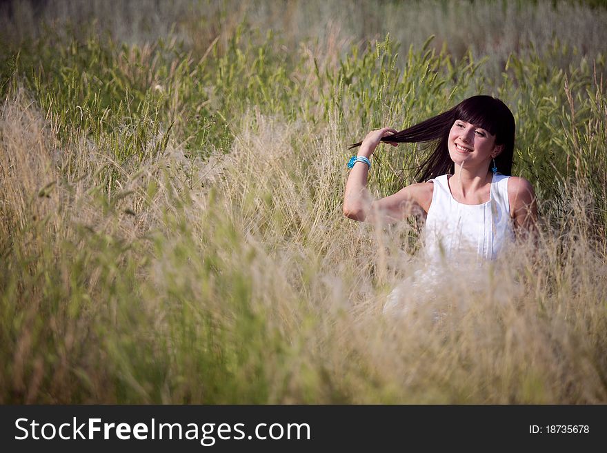 Happy girl in the grass touching her hair