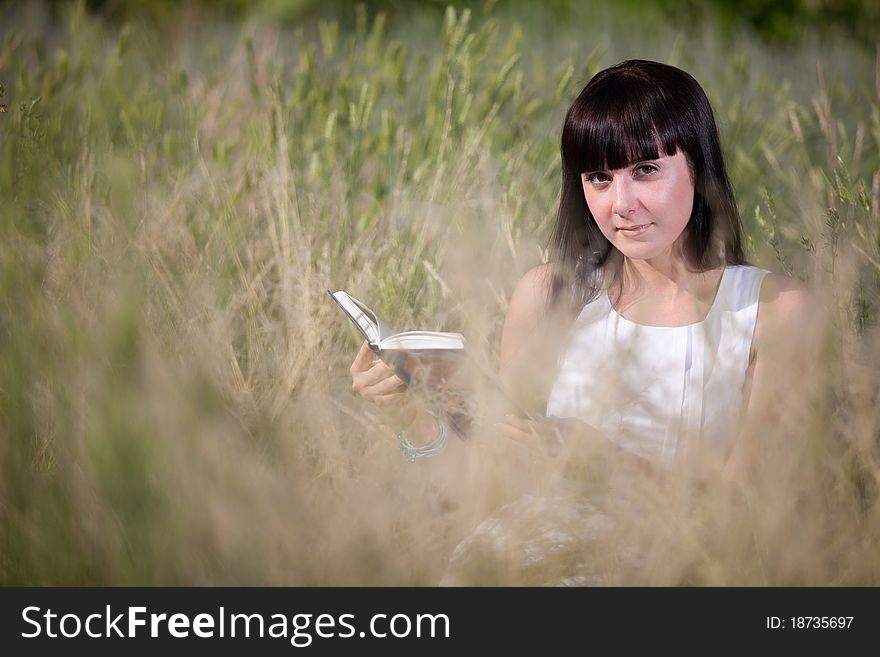 Girl reading a book in the grass