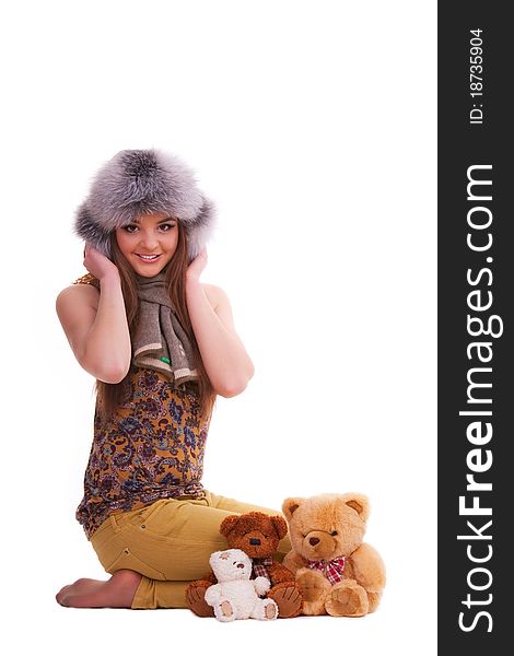 Beautiful brunette in a fur hat sitting next to a few teddy bears
