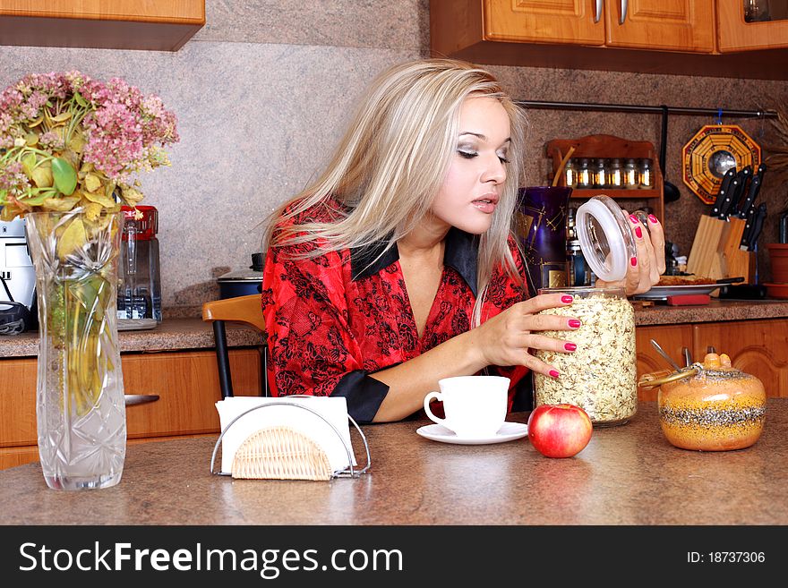 Woman taken jasmin petals for breakfast with apple and cup of hot drink in the kitchen