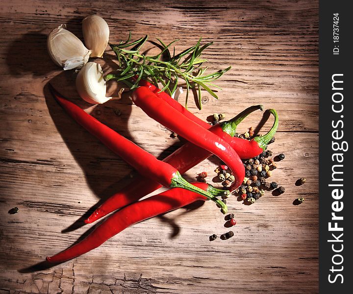 Red hot chili peppers with other spices on wooden background