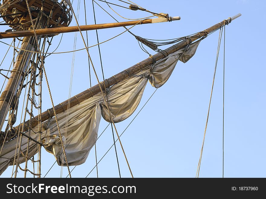Mast with half-hoisted sail against blue sky. Mast with half-hoisted sail against blue sky