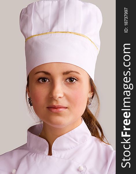 Young woman in white chef dress with hat. Young woman in white chef dress with hat