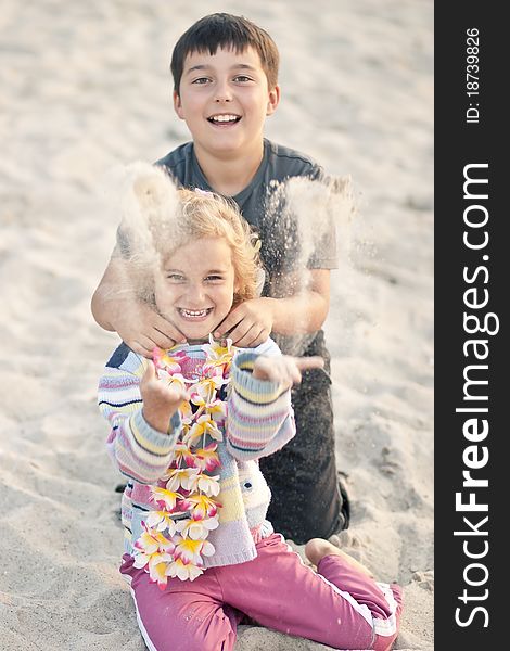 Boy with little girl throwing sand on a beach. Boy with little girl throwing sand on a beach