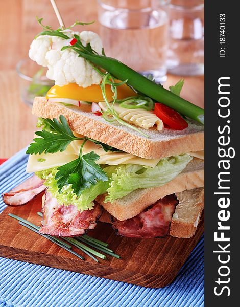 Bacon and cheese sandwich garnished with fresh vegetables
