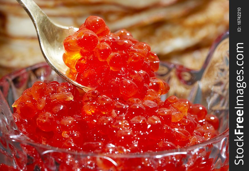 Studio photography tablespoons with red caviar on the unfocused background of pancakes