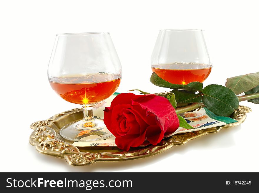 Roses and glasses of brandy on a tray isolated on white background. Roses and glasses of brandy on a tray isolated on white background