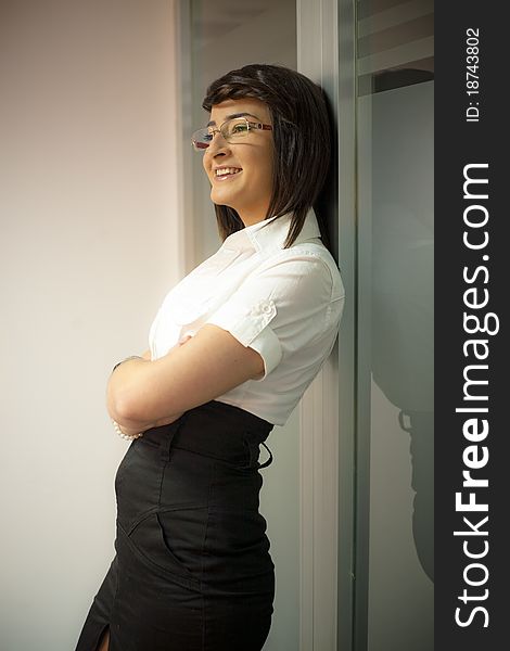 Smiling person dressed as businesswoman, leaning to a glass wall. Smiling person dressed as businesswoman, leaning to a glass wall.