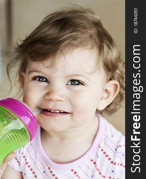 A cute little girl drinking from a sippy cup, selective focus on face. A cute little girl drinking from a sippy cup, selective focus on face