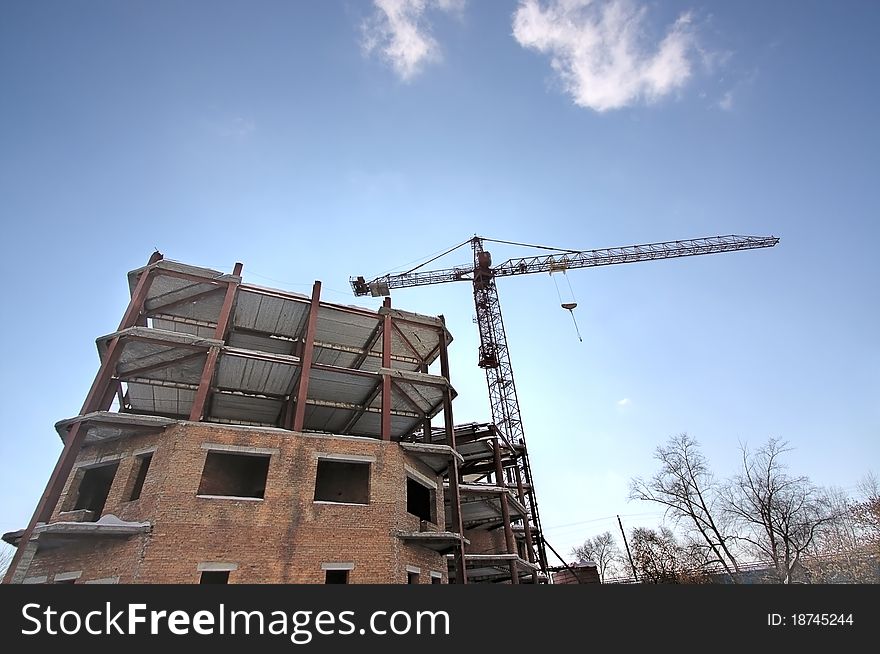 Tower crane near  house under construction on  background of  sky. Tower crane near  house under construction on  background of  sky.