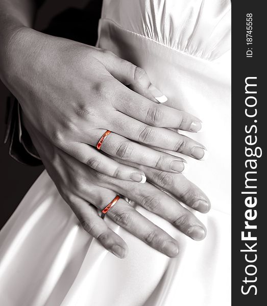 Block and white picture of the hands of a bride and a groom with golden wedding rings (accent on the golden rings)