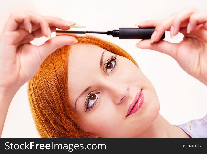 Beautiful young woman applying mascara on her eyelashes. Beautiful young woman applying mascara on her eyelashes