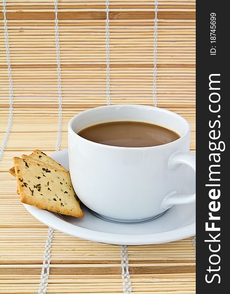 Coffee. White porcelain cup and three biscuit on a mat