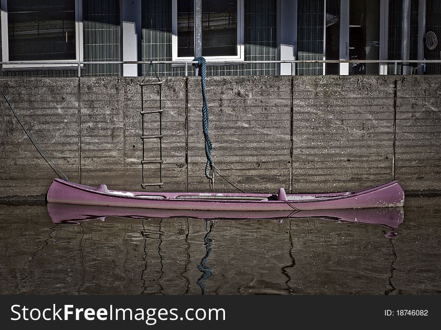 Purple canoe in Danish river close to house in Kolding city.