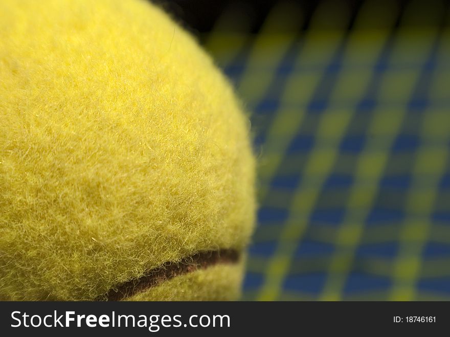 Yellow tennis ball close-up and blurred racket background. Yellow tennis ball close-up and blurred racket background.