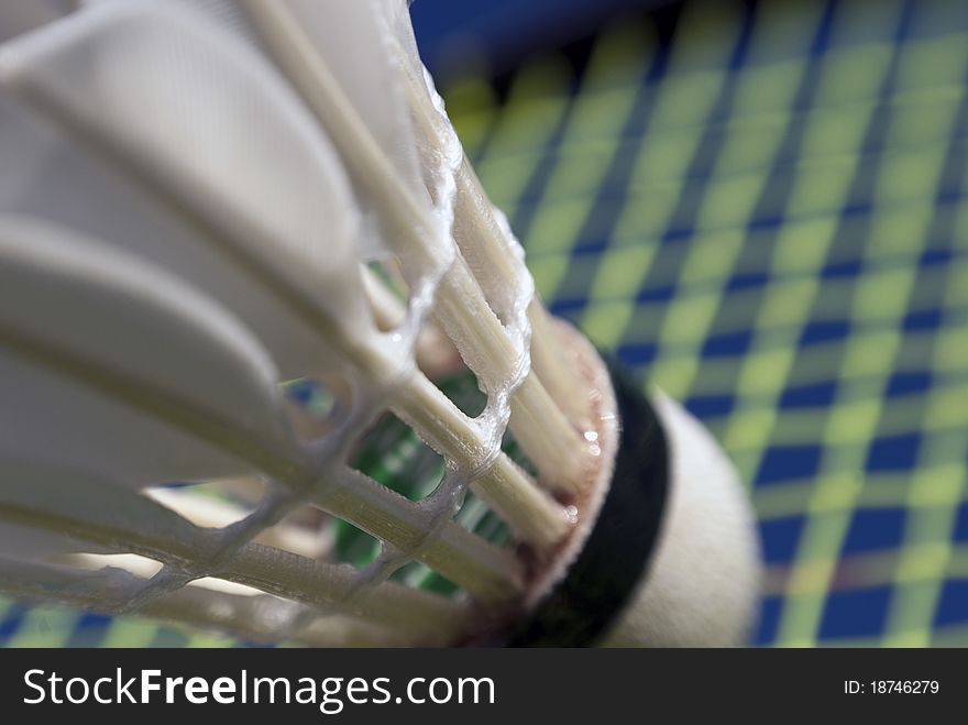 Abstract Badminton action close-up with shuttlecock and racket strings.