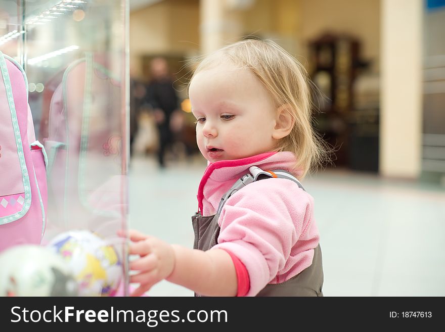 Adorable baby looking to baby toys in shop window