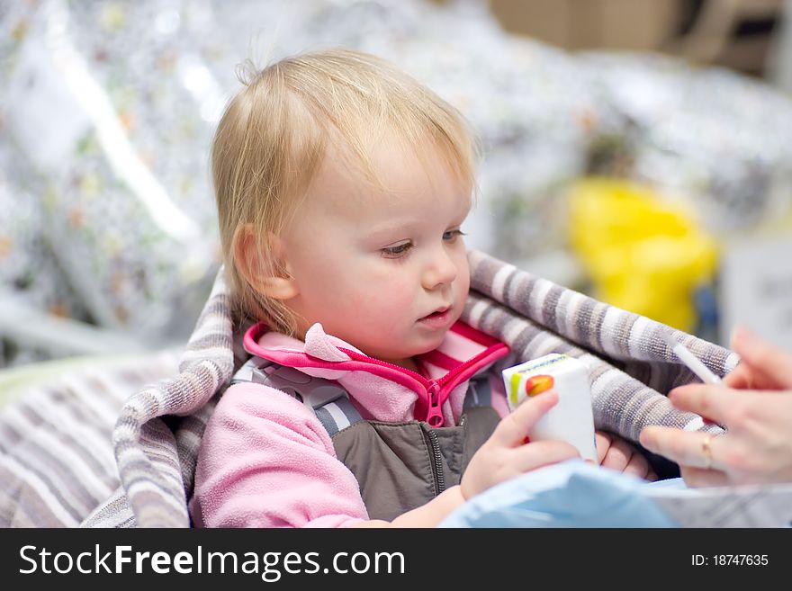 Adorable baby sit in shopping cart with small pack of juice give by mother. Adorable baby sit in shopping cart with small pack of juice give by mother