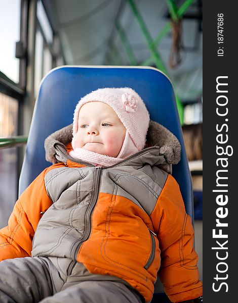 Adorable baby riding in city bus on seat place. Looking to window. Adorable baby riding in city bus on seat place. Looking to window