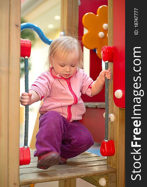 Young adorable baby climb to baby slide on playground in mall