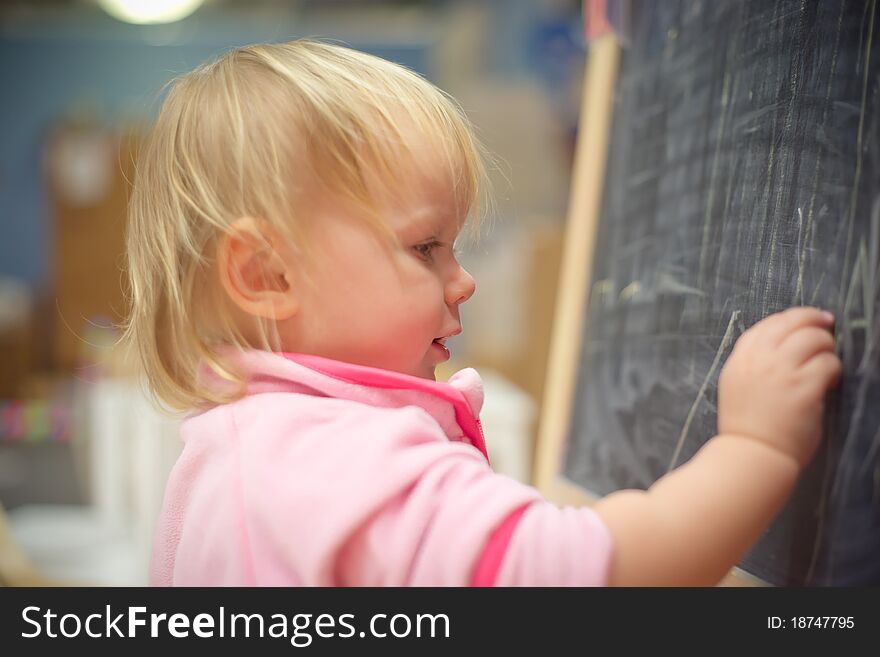 Adorable baby draw lines and figures on blackboard with chalk. Adorable baby draw lines and figures on blackboard with chalk