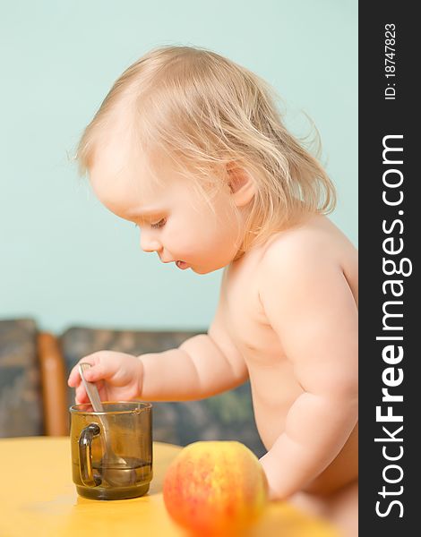 Adorable baby drink a tea on kitchen with small spoon. Adorable baby drink a tea on kitchen with small spoon