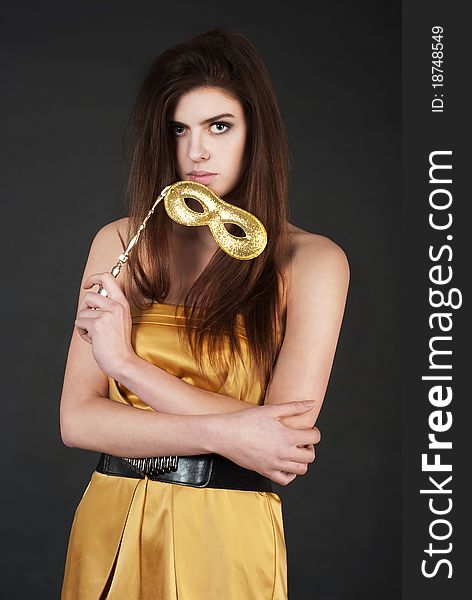 Beautiful young woman holding a carnival mask wearing against black background