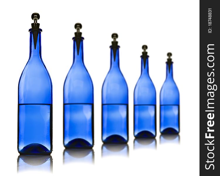 Five blue glass bottles with water