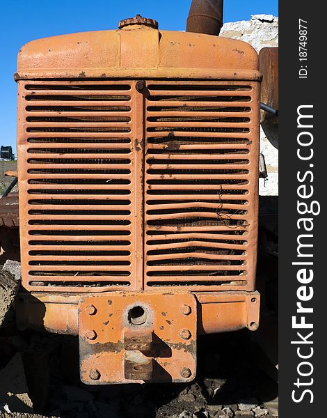 Front view of an old, abandoned, reddish tractor