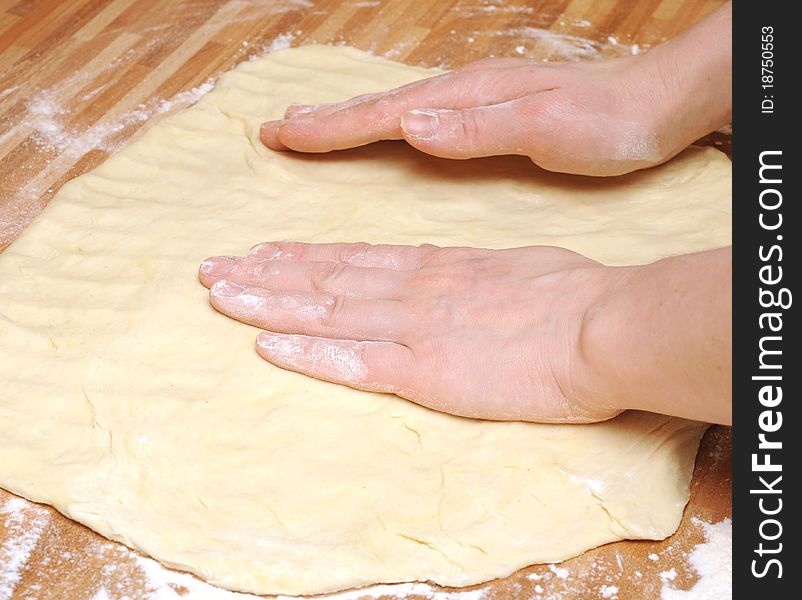 Preparing pizza dough in a kitchen.