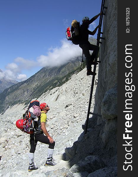 Climbers using a steel ladder to climb from the Mer De Glace morraine towards the Charpoua hut, in the Alps, near Chamonix, Mont Blanc region, France. Climbers using a steel ladder to climb from the Mer De Glace morraine towards the Charpoua hut, in the Alps, near Chamonix, Mont Blanc region, France